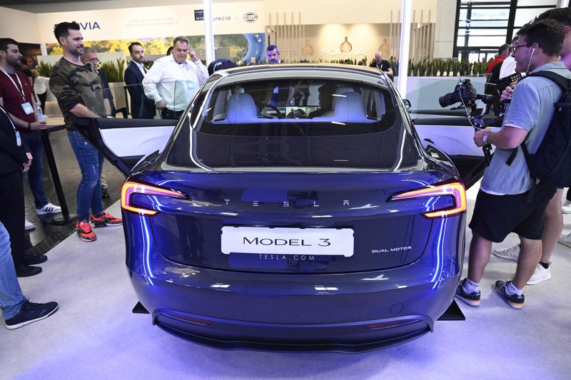 ▲参与者围绕参观特斯拉(Tesla)改进版的Model 3电动车。(法新社)